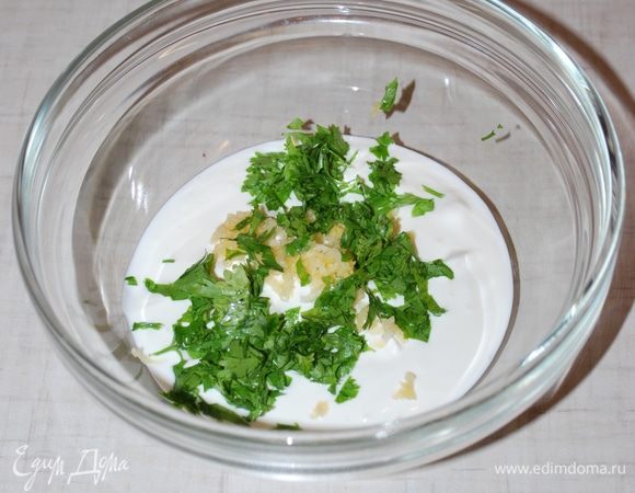 Тем временем готовим соус. В сметану добавляем свежий чеснок и кинзу, немого солим по вкусу.