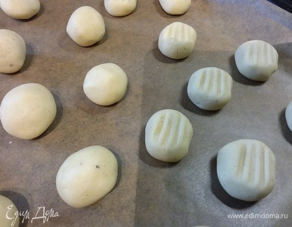 Можно тесто скрутить в колбасу и нарезать на кусочки величиной с вишню, а можно отщипывать тесточки, формируя шарики, выкладывать на некотором расстоянии друг от друга на противень. Взять вилку и прижать ею шарики. Если она будет клеиться к тесту, притрусить чуть-чуть мукой. У меня получилось 60 штук. 