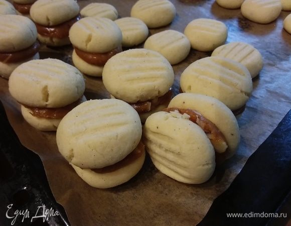 Часть печенья я смазала оставшейся от тарталеток карамелью. А для крема из оригинального рецепта нужно взбить масло комнатной температуры с сахарной пудрой в течение 5 минут. С лимона снять цедру и выдавить сок. Вмешать цедру и сок в масляный крем. 