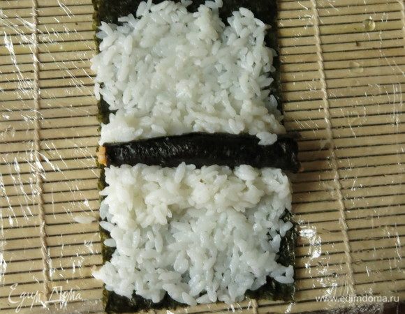 Цилиндрик риса формируем в виде листка — один край делаем острым. В центре нори кладем цилиндр цветного, тыквенного риса, закрепляем его рисом.