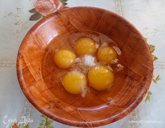 В чашку разбиваем куриные яйца. Добавляем соль и сахар.