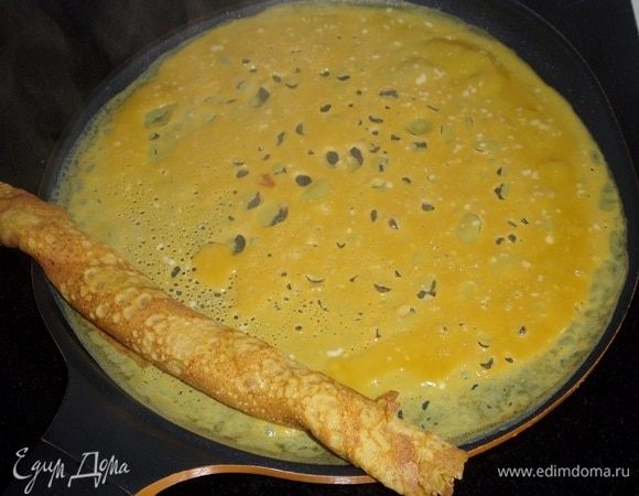 Сразу же на один край яичного блина кладем ранее завернутый рулет.