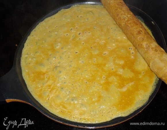 Смазать сковороду маслом и налить очередную порцию яичной смеси. Сразу же положить ранее завернутый рулет.