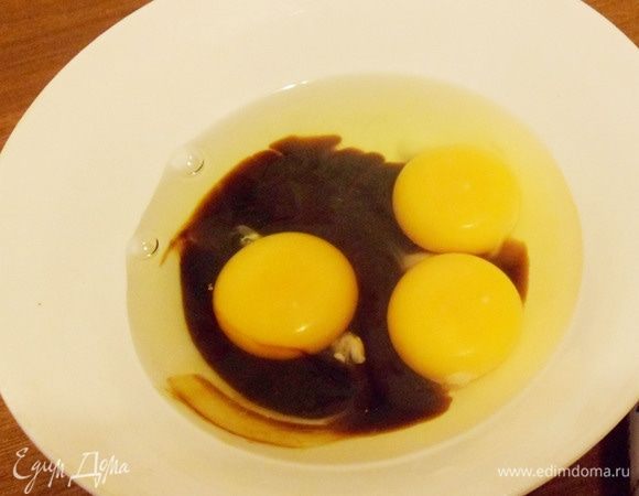 Яйца перелить в миску, добавить две столовые ложки соевого соуса.