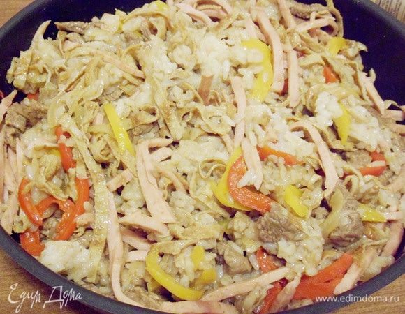 В сковороду к луку с перцем выложить рис, обжаренную говядину, ветчину и полоски омлета. Влить оставшийся соевый соус и приправить острым красным перцем. Все тщательно перемешать и прогреть на огне около двух минут. При необходимости добавить соль (я не добавляла).