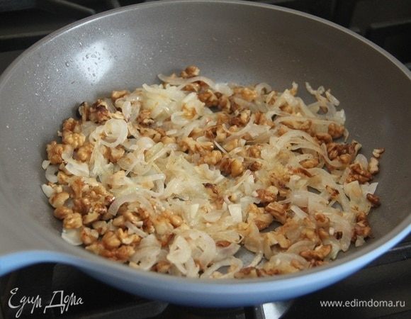 Лук нарезать полукольцами и обжарить на растительном масле до золотистого цвета. Добавить рубленые грецкие орехи и чеснок. Обжарить еще пару минут.