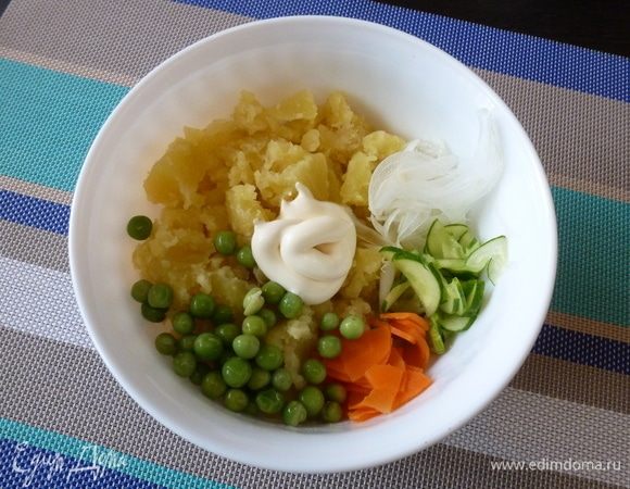 Соединим в салатнике мятый картофель, лук, огурец, морковь и зеленый горошек. Заправим майонезом.