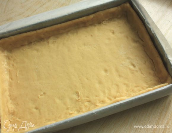 Разъемную форму для тарта (11х35 см) смазать жиром. На посыпанной мукой поверхности раскатать тесто в прямоугольник 13х37 см и перенести его в форму, прижать к стенкам. (У меня в этот момент не было под рукой разъемной формы, поэтому я застелила противень пергаментом, чтобы можно было легко вынуть базу для тарта.) Излишки теста обрезать, дно наколоть вилкой.