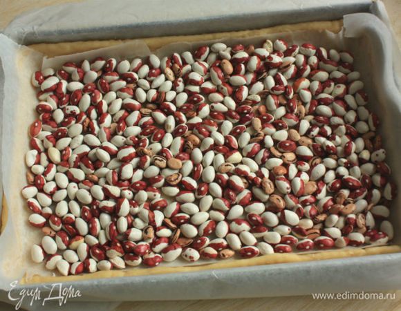 Закрыть тесто пекарской бумагой, сверху высыпать не менее 1 стакана сухого гороха или фасоли. Выпекать в разогретой до 200°С (с конвекцией до 175°С) духовке около 10 минут. Удалить бумагу и горох и выпекать при той же температуре еще 5-10 минут до золотистого цвета. Вынуть основу для тарта из формы и остудить.