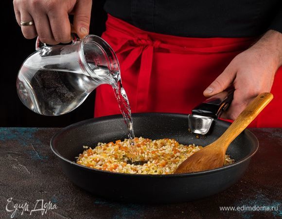Влейте 2 стакана воды, добавьте соль и перец молотый. Доведите ризотто до кипения и тушите в течение 15 минут под крышкой.