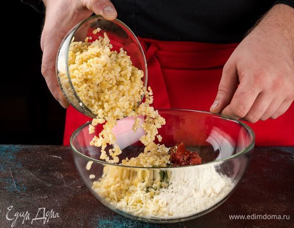 Добавьте к булгуру томатную пасту, сыр, розмарин и муку. Посолите по вкусу и все хорошо перемешайте. Добавьте 2 ст. л. оливкового масла и хорошо вымесите до однородной массы. По желанию, вместо свежего можно добавить сушеный розмарин.