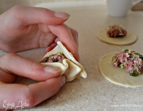 На каждый кружочек теста положите по 1 ч. л. начинки и сформируйте пельмени в виде полумесяца с защипами с одной стороны.