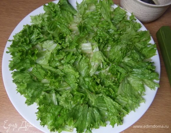 На большую плоскую тарелку нарезать или порвать салатные листья.