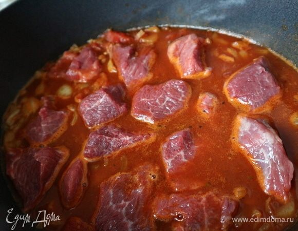 Поставить на средний огонь, добавив примерно половину стакана воды и довести до кипения. Добавить обжаренный лук, мясо и тушить все вместе 2,5 часа, накрыв крышкой. Мясо должно быть лишь слегка покрыто жидкостью. Если вам покажется, что жидкости много, откройте крышку и выпарите жидкость. Периодически перемешивать и при необходимости подливать воду. Через полтора часа после начала процесса жидкость начнет становиться густой. Когда мясо будет почти готово, добавить воды и перемешать. У меня ушло еще 400 мл воды, которую я добавляла постепенно по мере приготовления. Пусть гуляш готовится еще некоторое время, затем проверьте на вкус — не надо ли еще посолить. Смешать муку с небольшим количеством воды и добавить в гуляш примерно за 20-30 минут до готовности. Не забывать помешивать периодически, так как после добавления муки густой соус начнет немного прилипать к дну жаровни.