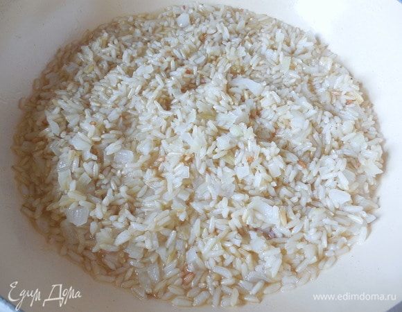 Тем временем подготовить вино, сыр и сливочное масло. Добавить рис к луку, готовить пару минут, перемешав, чтобы все рисинки покрылись маслом. Добавить вино и подождать, пока оно выпарится. Теперь влить 1 половник горячего бульона и увеличить огонь до среднего.  Готовить, часто помешивая, пока бульон почти полностью не впитается. Затем нужно повторить данную процедуру еще 3 раза. На приготовление ризотто уйдет примерно 20 минут. Готовое ризотто должно иметь кремовую консистенцию, а рис должен быть аль денте. Пока ризотто доходит до готовности, 2 веточки петрушки мелко нарубить.
