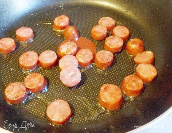 На сковороду налить немного оливкового масла и обжарить копченые колбаски.