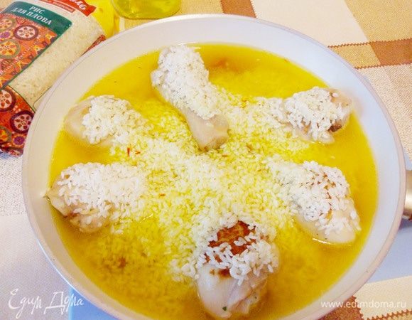 В общую сковороду добавить рис и часть бульона с шафраном. Довести до кипения, затем убавить огонь и готовить под крышкой.