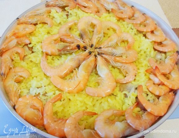 Пришло время добавить крупные размороженные креветки в панцире. Аккуратно разложить поверх риса.