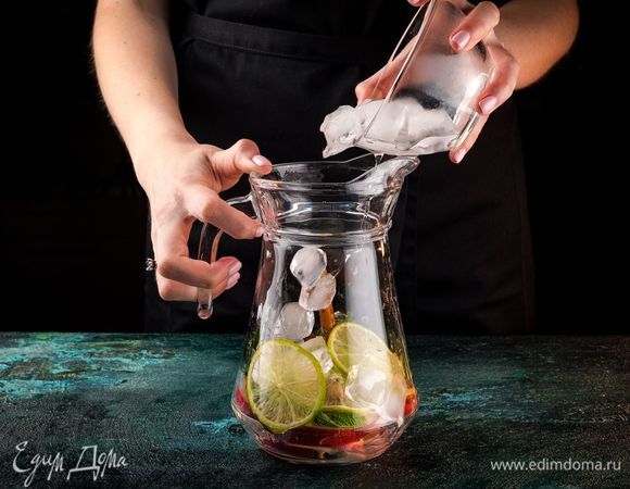 В емкость для лимонада сложите дольки нектарина, палочки корицы, несколько кружочков лайма, листья мяты и лед. 