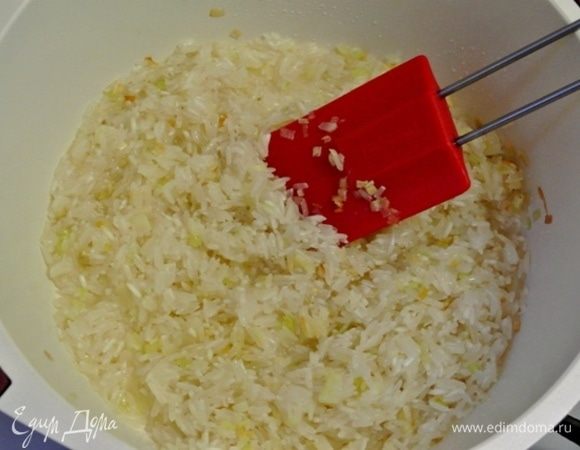 Промыть рис холодной водой. Выложить промытый рис к пассерованному луку, обжарить 1-2 минуты.
