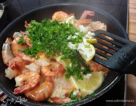 Через 3 минуты добавить чеснок, лимоны и петрушку, соль и перец и жарить до готовности. Это займет в зависимости от величины креветок в общей сложности 6–10 минут.
