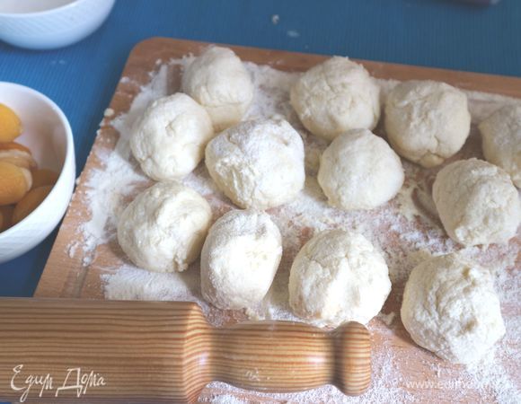 Разделить тесто на 12 кусочков, скатать в шарики на поверхности, хорошо присыпанной мукой (можно добавить на поверхность еще немного манной крупы). 