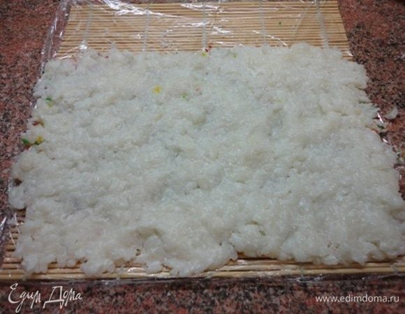 Смачивая руки в воде, распределить рис поверх кокосовой стружки.