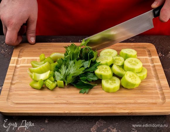 Огурец очистите и нарежьте на кусочки, также нарежьте сельдерей и петрушку.