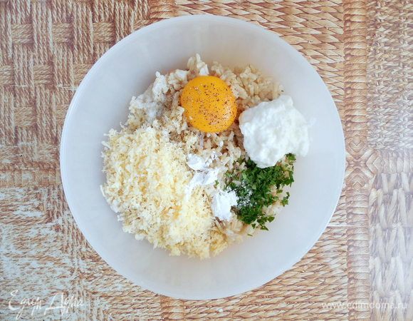 Добавить к рису желток, петрушку, йогурт,  натертый сыр, разрыхлитель и хорошо перемешать. Приправить по вкусу солью и перцем (но помните, что сыр соленый!).