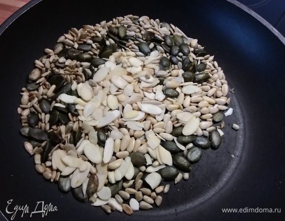 В отдельной сковороде соединить семечки, орешки и миндальные лепестки, обжарить. 