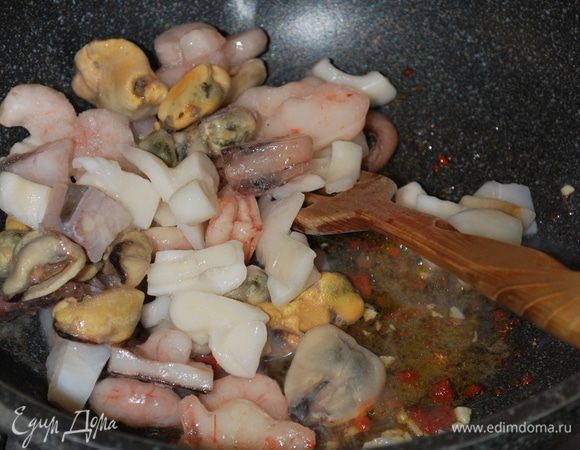 К чесноку и пасте добавляем морской коктейль, обжариваем до готовности.