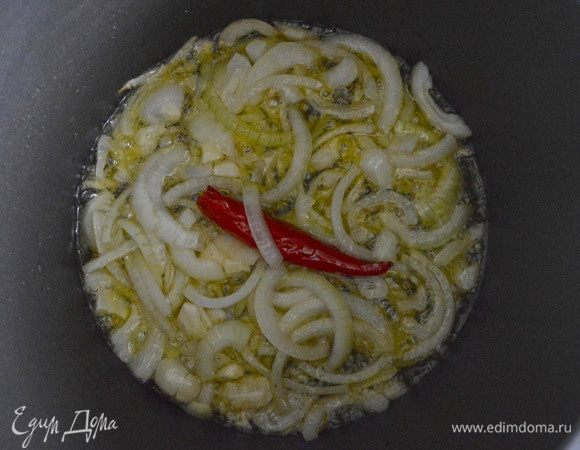 Выложить в масло нарезанный лук, раздавленный чеснок, стручок острого перчика, слегка обжарить до золотистого цвета лука.