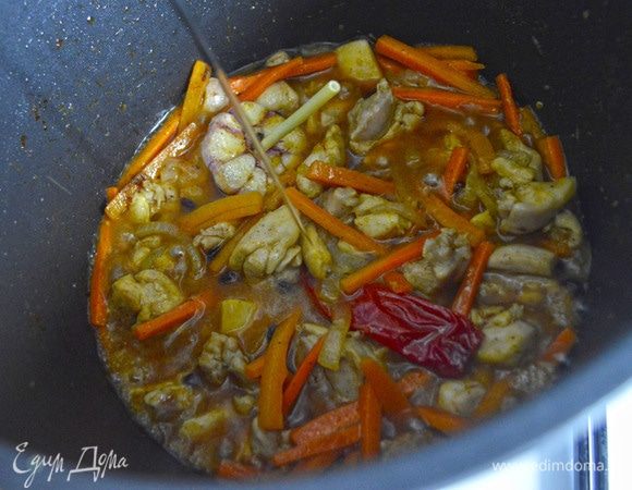 Залить в казан холодную воду так, чтобы она покрывала морковь. Проварить 20 минут с момента закипания на среднем огне под закрытой крышкой. Затем достать стручок перца и головку чеснока.