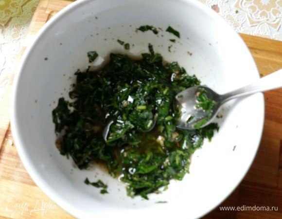 Сделаем соус из петрушки. Для этого в миске смешаем мелко порезанную петрушку, с добавлением к ней соли, сушеного базилика, чеснока, оливкового масла, смеси перцев. Немного потолочь ступкой, а можно и в блендере измельчить до однородной массы. 