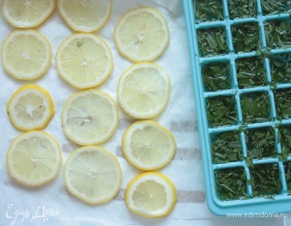 В формочки для льда выложите сначала отложенную треть зелени, которую вы крупно порвали, а затем залейте настоем. Один лимон нарежьте на тонкие-тонкие дольки. Отправьте все охлаждаться в морозилку.