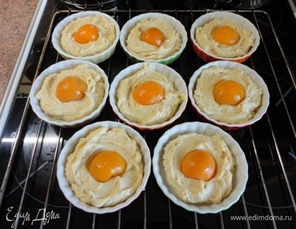 Если формочки не силиконовые, то лучше их смазать растительным маслом и посыпать сухарями или манной крупой. Выложить тесто, а в середину по половинке абрикоса.