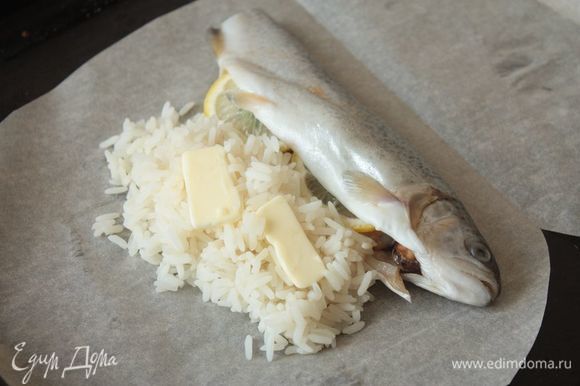 Рядом с рыбой выкладываем рис, а на него — буквально пару долек сливочного масла, чтобы риск не получился сухим.