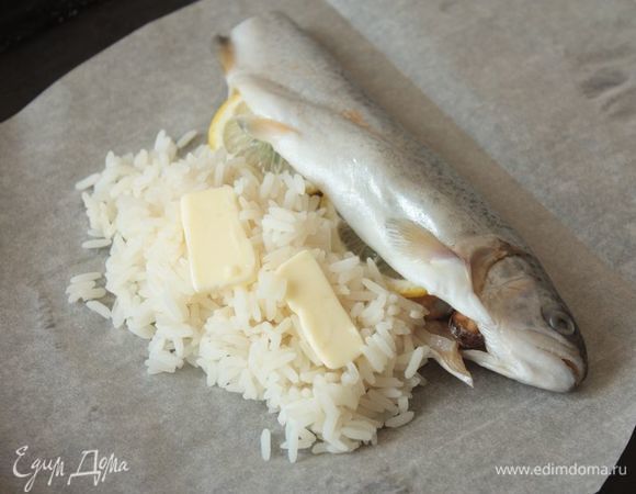 Рядом с рыбой выкладываем рис, а на него — буквально пару долек сливочного масла, чтобы риск не получился сухим.