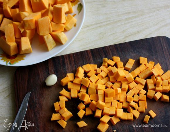 Тыкву вымыть, нарезать клиньями, удалить семена с волокнистой мякотью. Ножом для чистки овощей снять кожуру и 3/4 тыквы нарезать на куски, оставшуюся часть мелкими кубиками.

