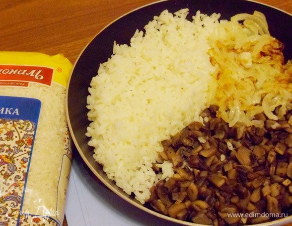 Выложить к шампиньонам отварной рис и обжаренный лук.