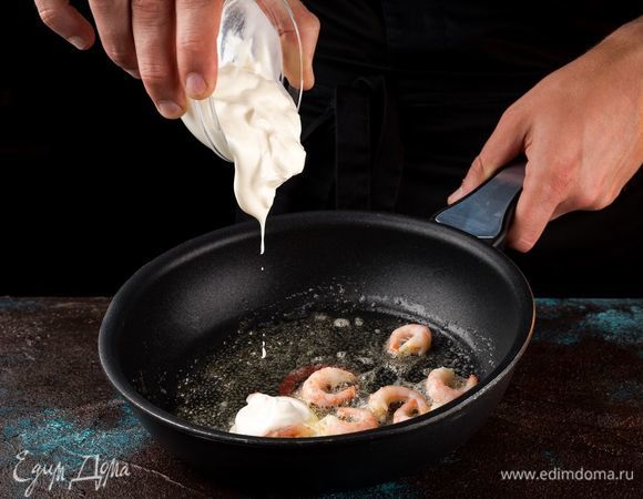 Добавьте сметану, тщательно перемешайте и оставьте на огне на 1 минуту. Когда сметана загустеет, приправьте креветки специями по вкусу и снимите с огня.