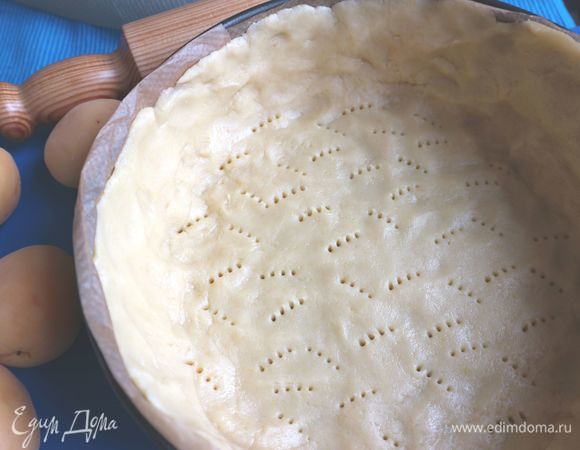 Достать тесто из холодильник, снять пленку, раскатать под размер формы. Дно и борта формы закрыть пекарской бумагой. Поместить тесто в форму, сделать высокие бортики из теста, так как заливки много. Наколоть тесто вилкой. Поместить в холодильник на 20 минут.