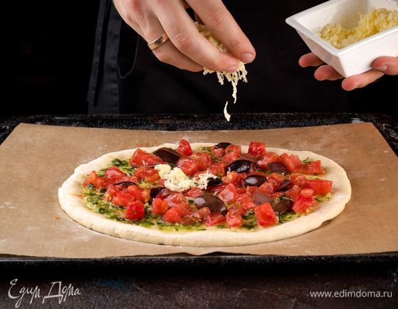 Нарежьте оливки на половинки, моцареллу натрите на терке и разложите все на тесто равномерно. 