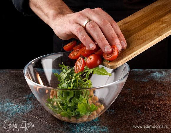 Помидоры черри нарежьте пополам, смешайте с фасолью и руколой, полейте маслом и лимоном.