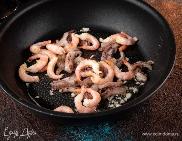 Обжарьте на оливковом масле креветки и щупальца кальмара, добавьте специи по вкусу, измельченный чеснок.