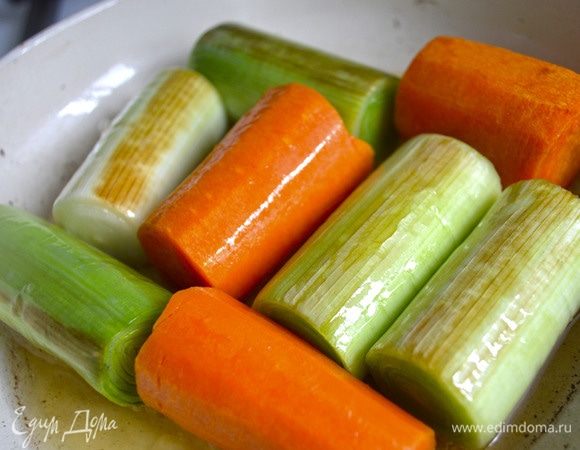 У порея удалить внешние листья, с моркови снять внешний слой, с долек чеснока снять шелуху. Налить в сковороду оливковое масло, обжарить овощи, переворачивая, со всех сторон до золотистой корочки. 