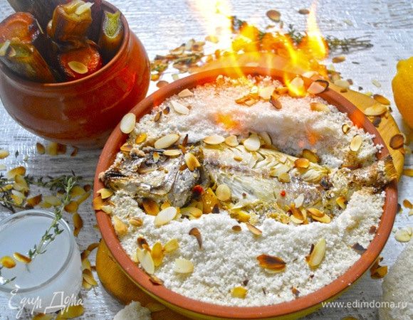 Достать рыбу из духовки, снять слой соли, аккуратно снять шкурку с рыбы. Часть ракии смешать с водой, положить в нее веточку тимьяна, подать в качестве напитка. Овощи подать на отдельном блюде и все украсить лепестками миндаля. Оставшуюся часть ракии нагреть (не кипятить!), полить ею рыбу и поджечь. Подать к столу. Приятного вам аппетита!