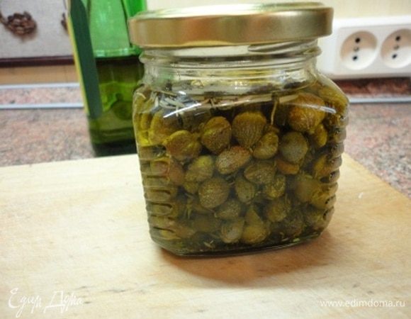 За неделю до приготовления салата, я подготовила каперсы. Для этого надо слить маринад, промыть и осушить каперсы. Оливковое масло с розмарином, тимьяном и орегано прогреть на водяной бане и залить этой смесью каперсы. До употребления выдержать в масле несколько дней. Я держала их неделю, оставшиеся каперсы так и хранятся в масле с пряными травами.