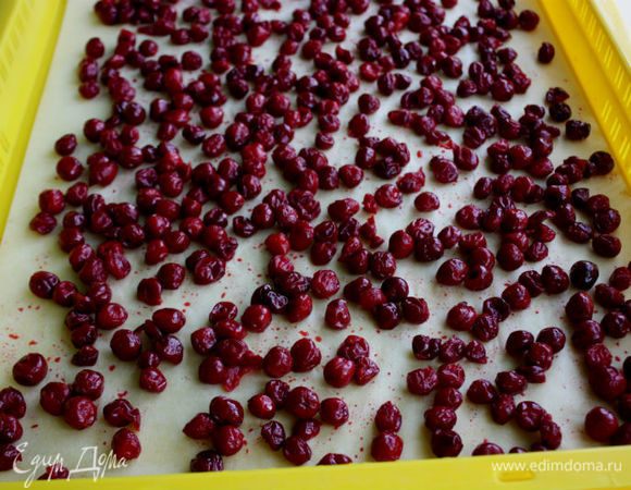 Большие противни застелить пергаментом и распределить вишню в один слой, оставляя промежутки между ягодами.