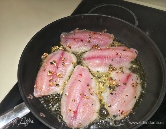 Поставьте сковороду на средне-сильный огонь, щедро налейте оливкового масла. Необходимо, чтобы дно сковороды было горячим, иначе корочка не пристанет к рыбе. Нужную температуру можно определить, брызнув пару капель воды на сковороду, она начнет слегка шипеть. Кладите тушки движением от себя панировкой вниз. Жарьте на этой стороне 3-4 минуты.